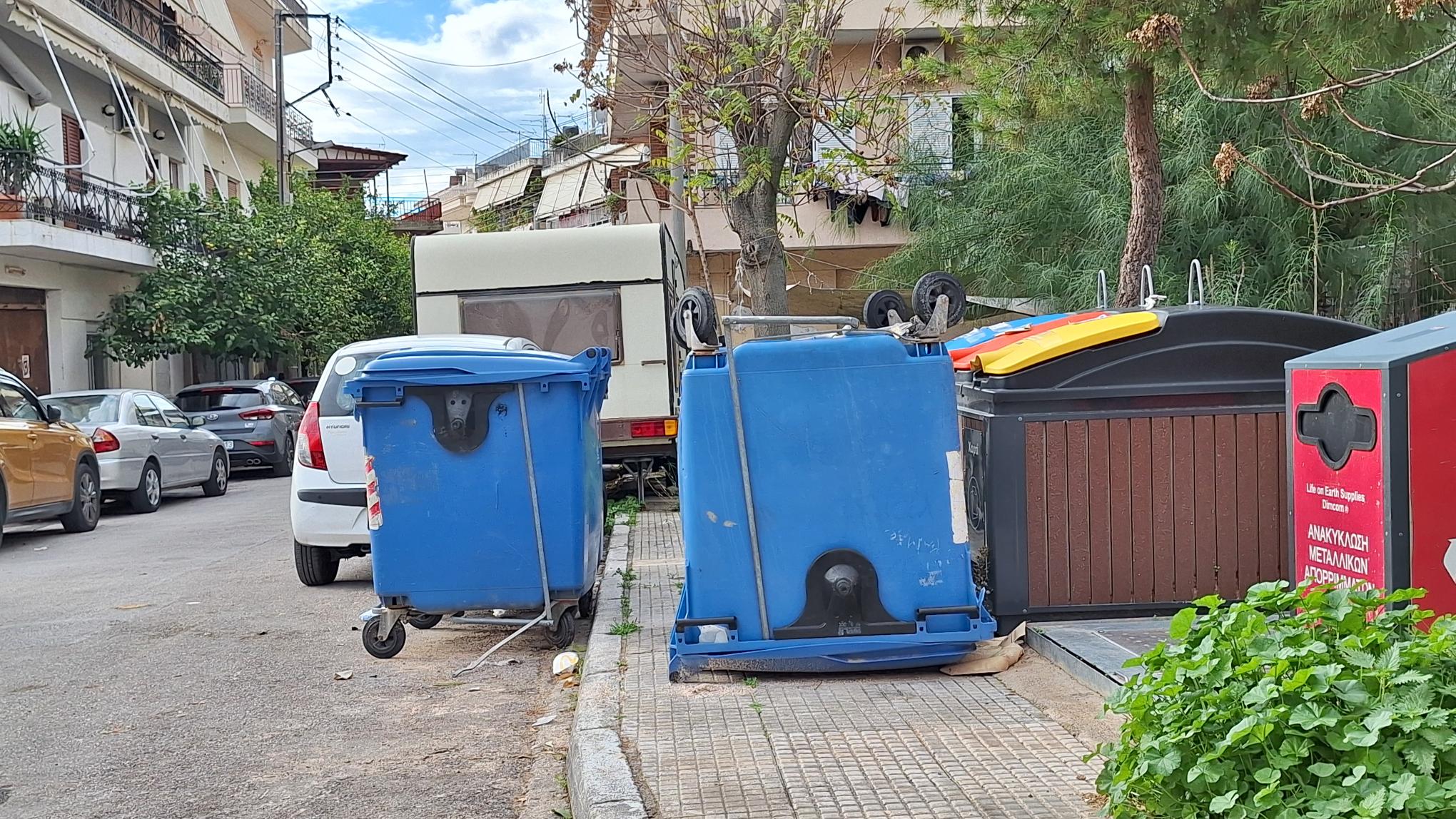 Αναποδογυρισμένος κάδος ανακύκλωσης στο πεζοδρόμιο της οδού Καραολή, επί μέρες